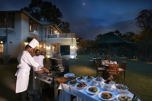 An outdoor dining area with a grill, multiple dining tables, and a large umbrella.