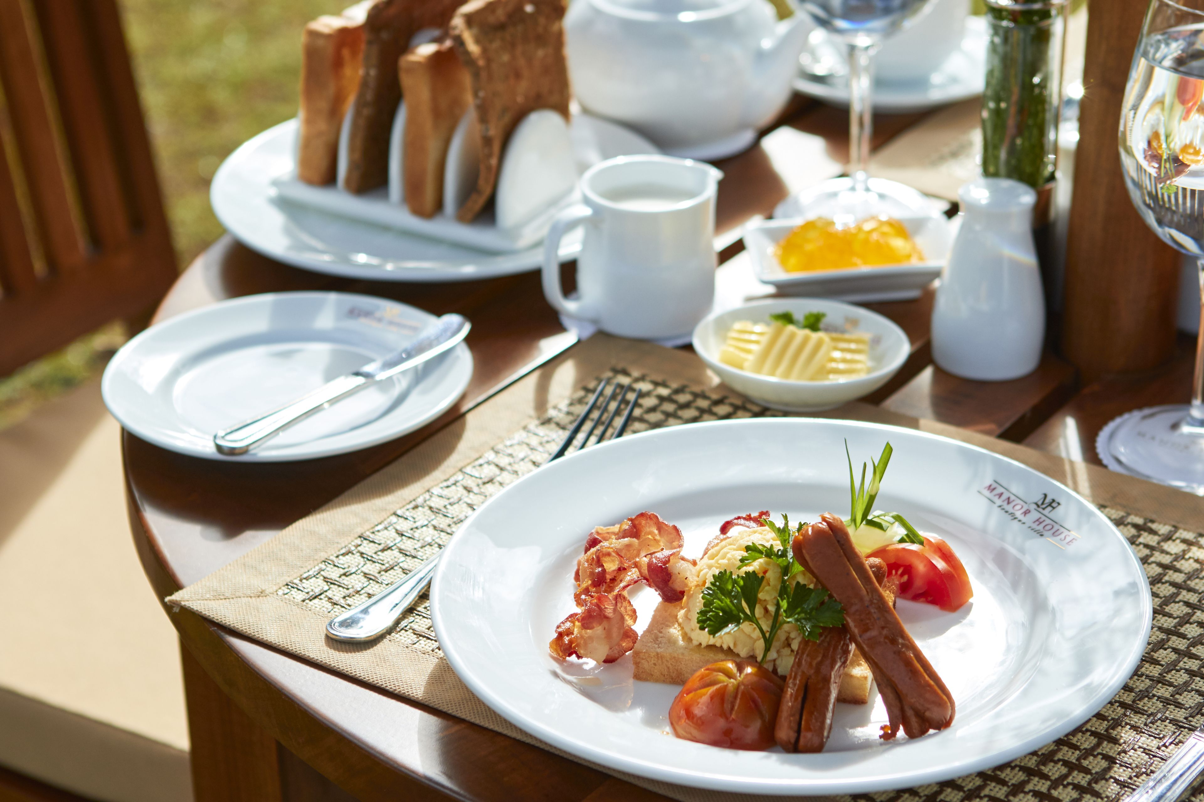 A table set for breakfast with plates of food, a teapot, and a glass of water.