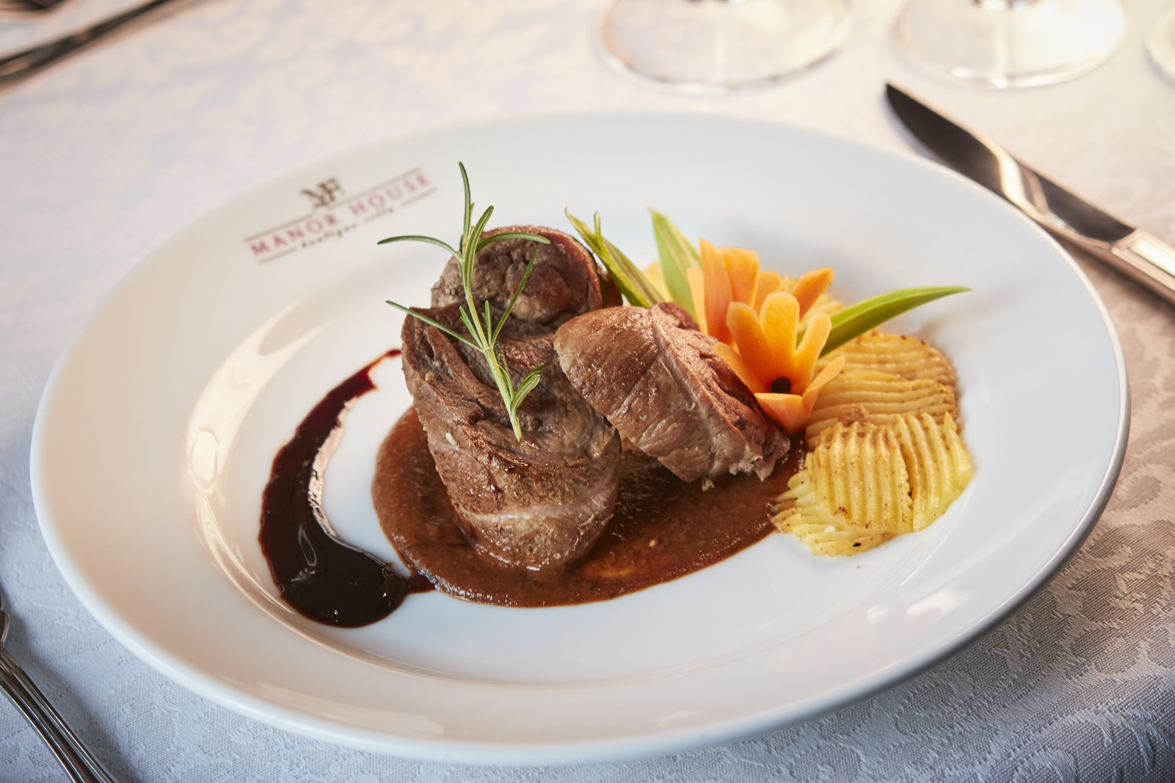 Een wit bord met een gerecht van vlees, groenten en saus.
