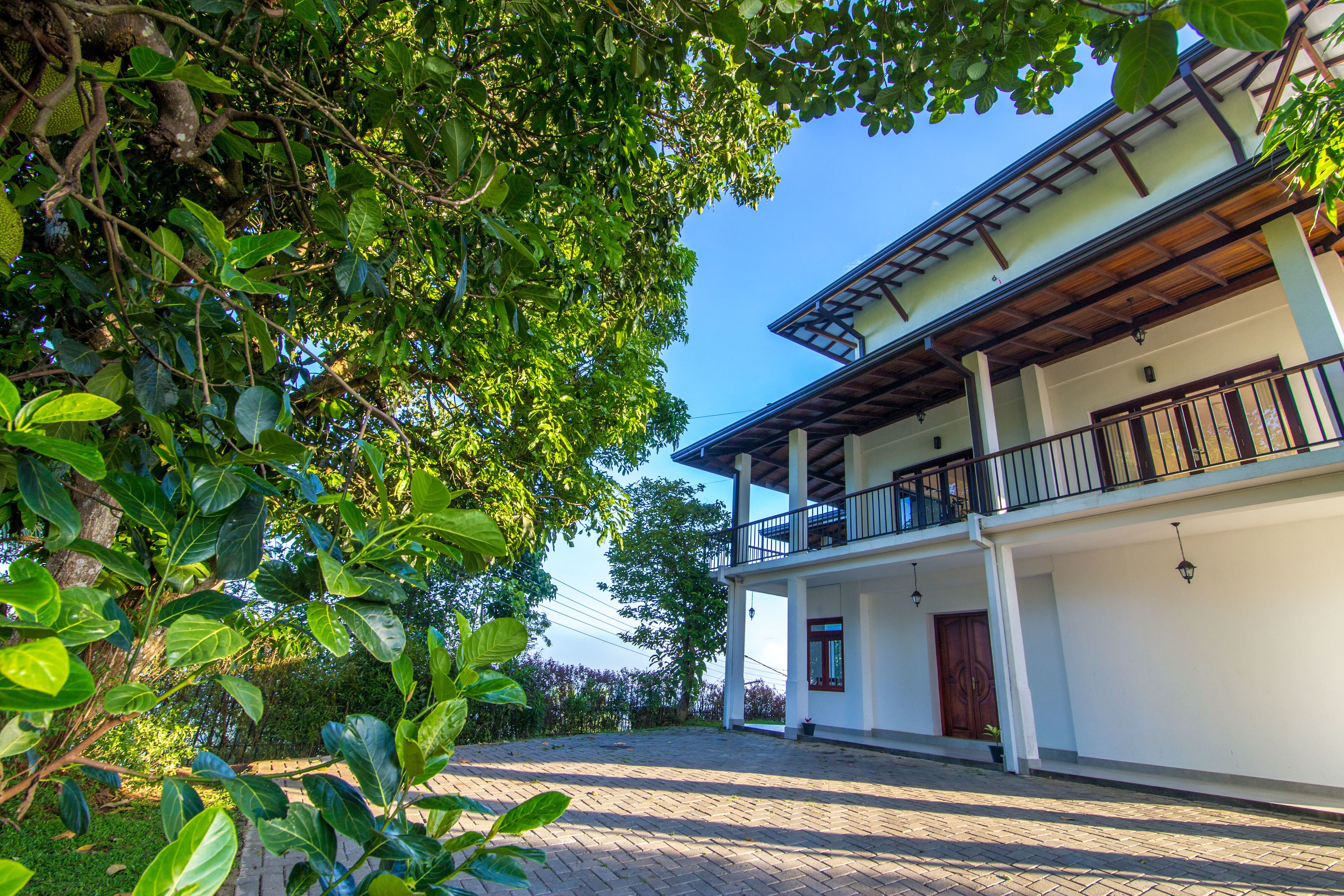 A two-story building with a balcony, surrounded by lush greenery.