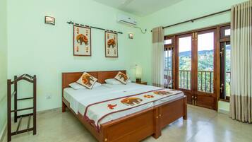 A bedroom with a large bed, a wooden ladder, a ceiling fan, and a view of the outdoors through a door.