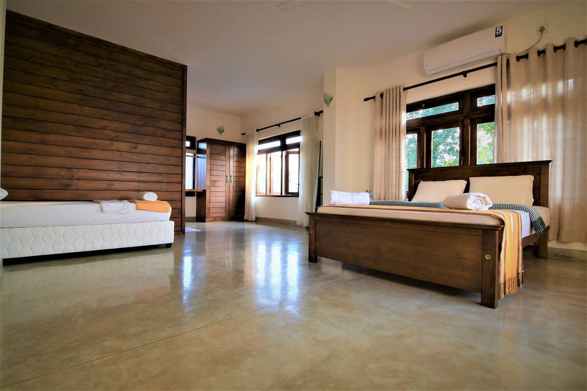 A bedroom with a wooden headboard bed, a white sofa, and a large window with curtains.