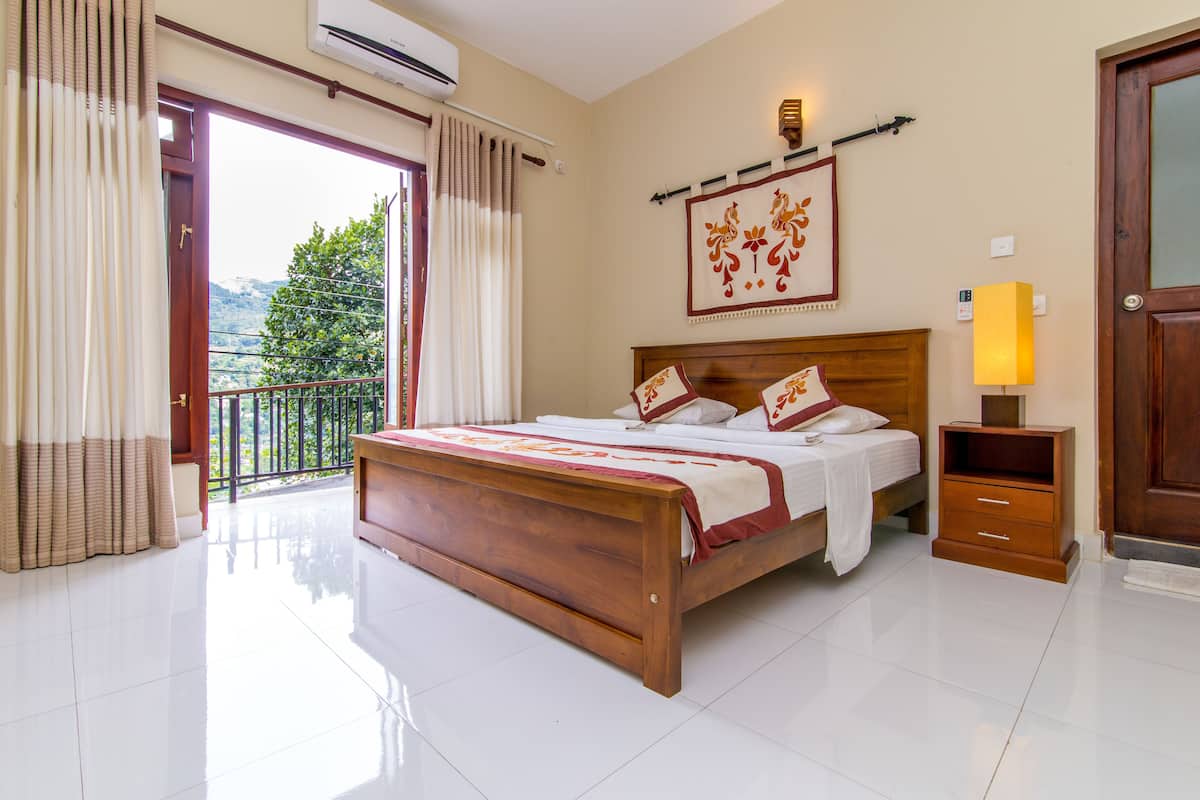 A bedroom with a wooden bed, a nightstand, a wall-mounted lamp, and a view of the outdoors.