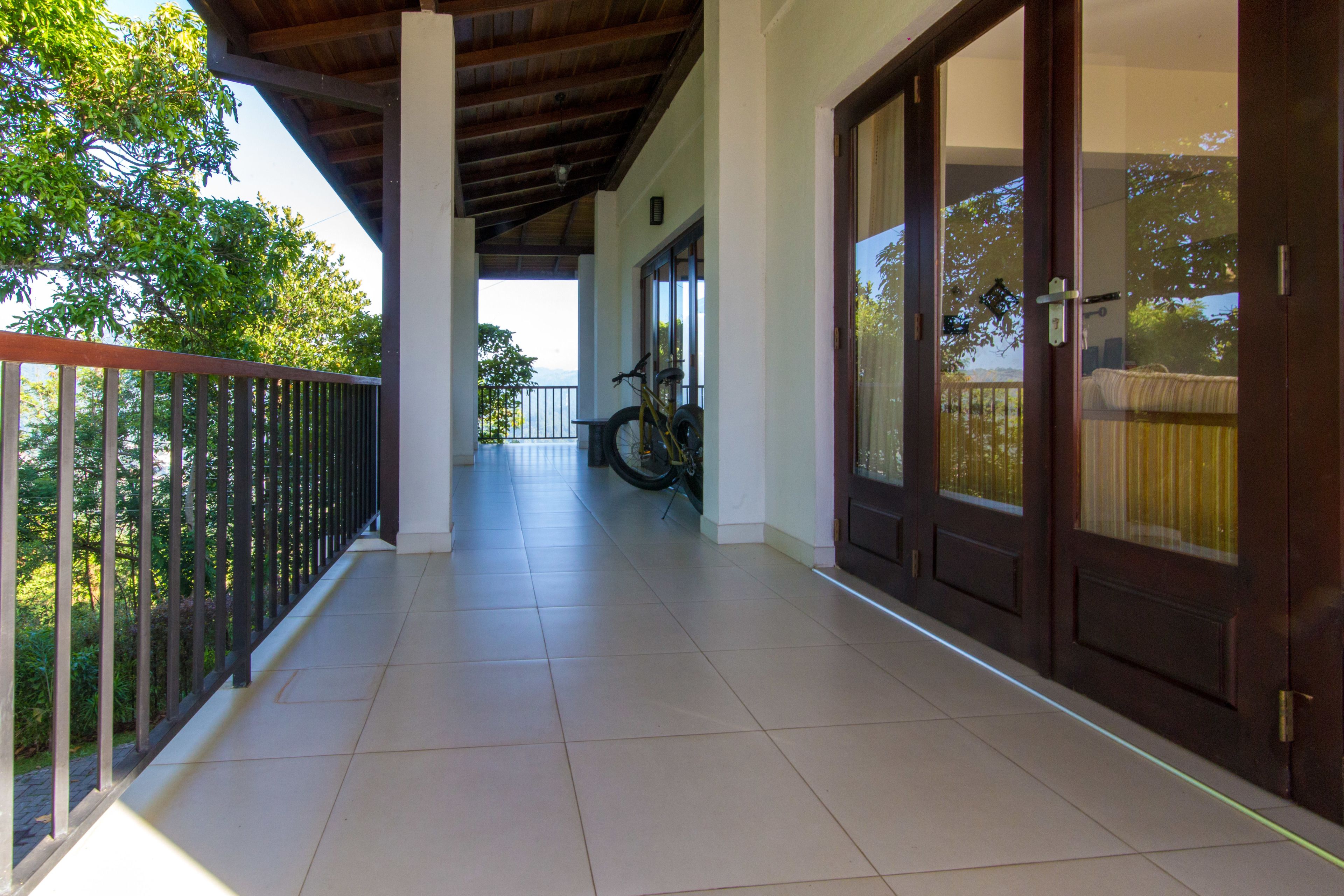 A covered balcony with a tiled floor, a bicycle, and a door with glass panels.