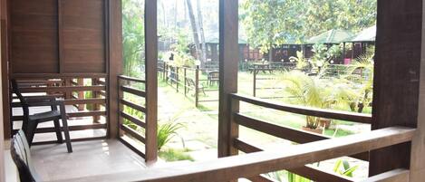 A wooden deck with benches, surrounded by lush greenery and a view of a tropical garden.