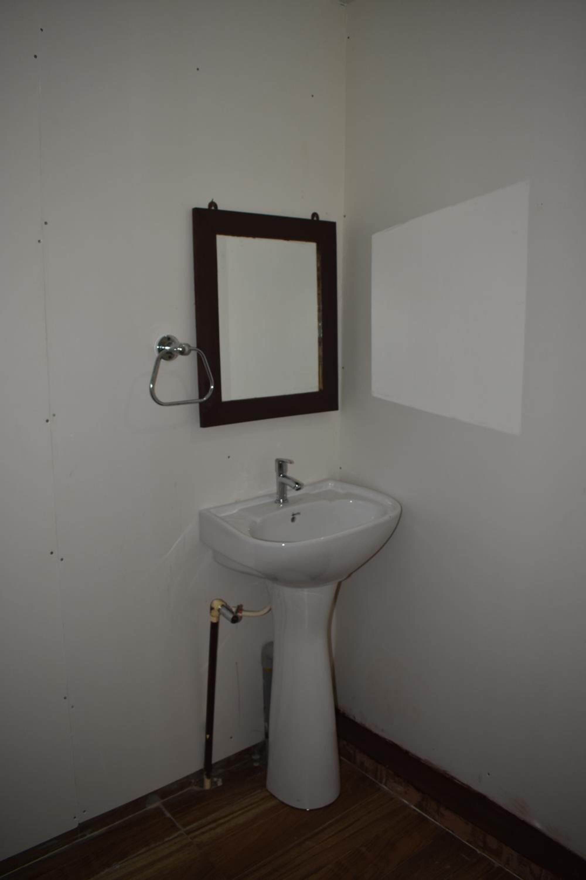Une salle de bain avec un lavabo blanc, un miroir à cadre foncé et un porte-serviettes.