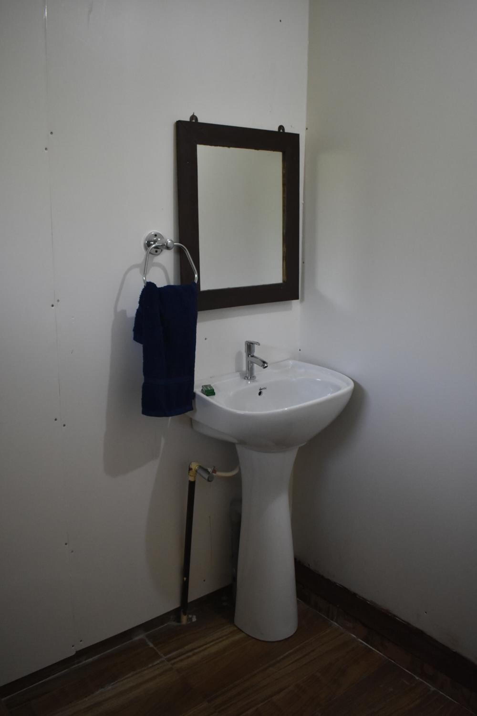 A bathroom with a white sink, a mirror with a dark frame, and a towel hanging on a metal rack.