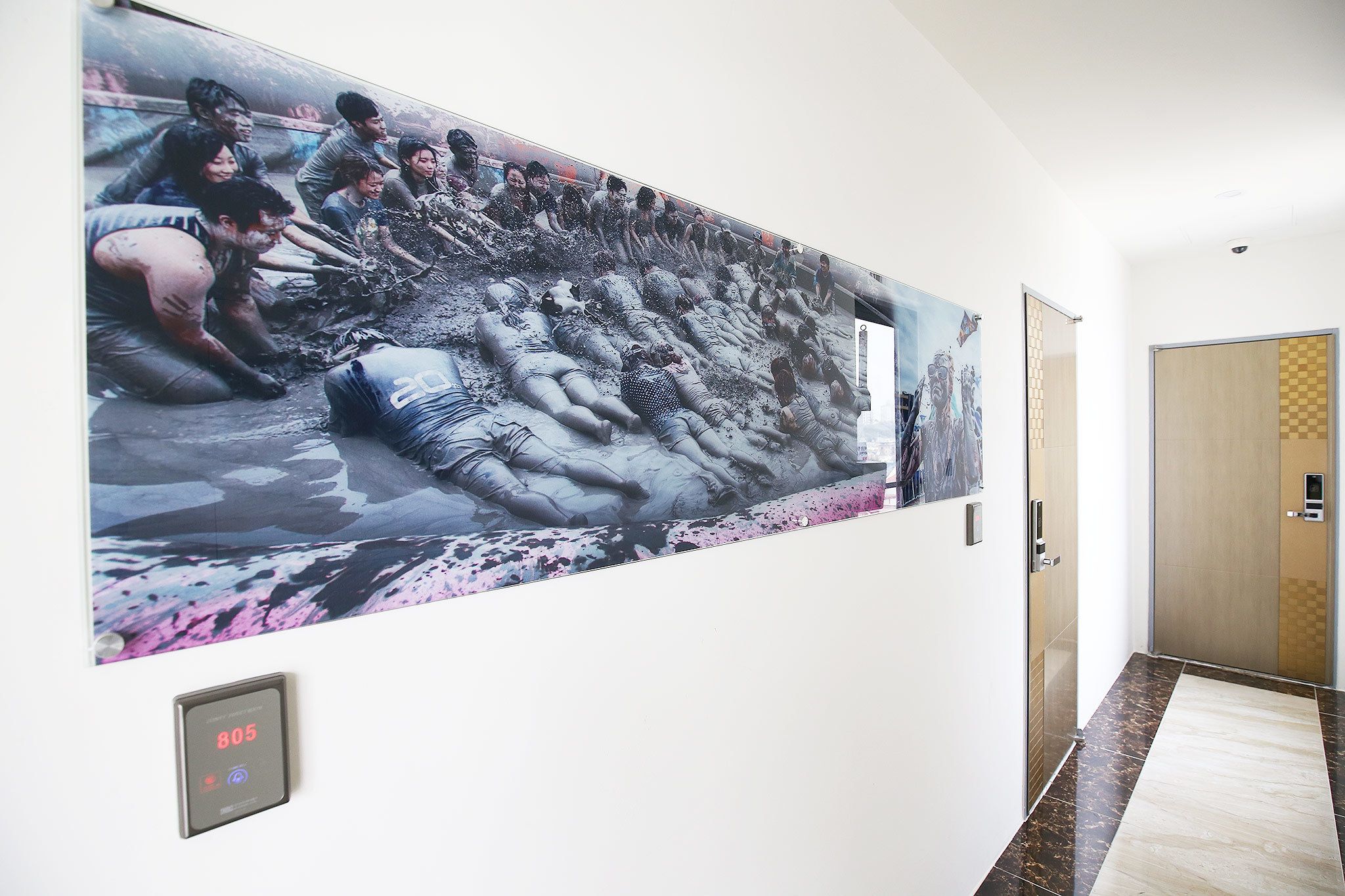 Corredor com um grande mural retratando um grupo de pessoas em uma cena enlameada.