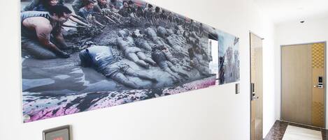 Un pasillo con un mural grande que muestra un grupo de personas en una escena embarrada.