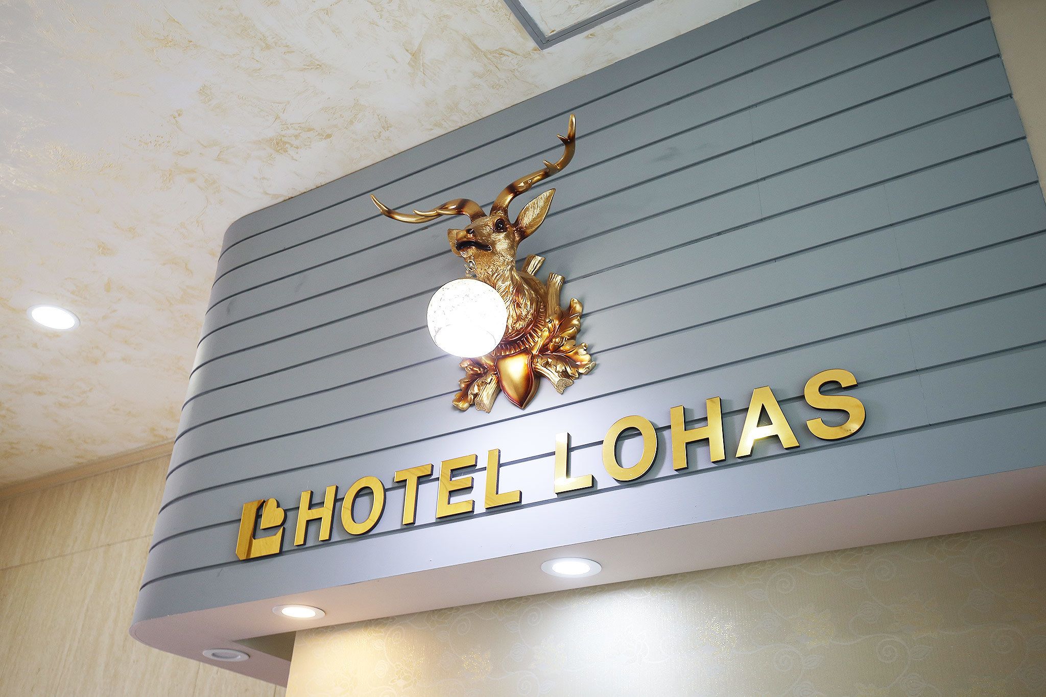 A hotel sign with a golden deer emblem and the name "HOTEL LOHAS".
