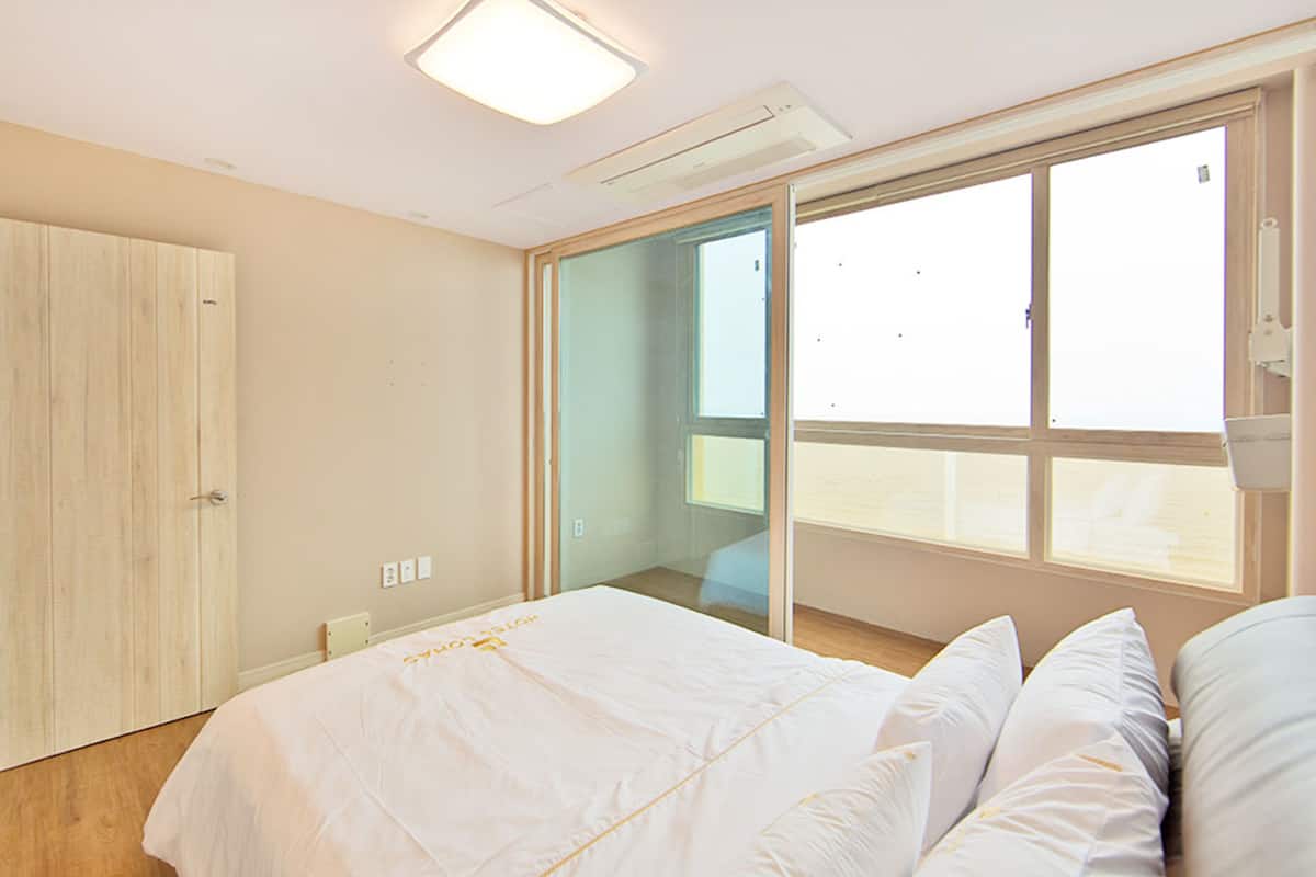Un dormitorio con cama, armario, puerta de vidrio corredera y ventana.
