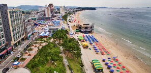 Un paysage urbain côtier avec une plage bordée de parasols colorés et une scène pour les événements.