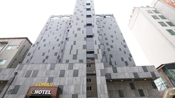 A tall hotel building with a modern design, featuring a prominent entrance and a sign for "LOHAS HOTEL".