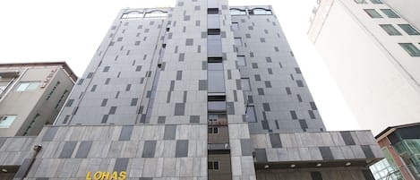 A tall hotel building with a modern design, featuring a prominent entrance and a sign for "LOHAS HOTEL".