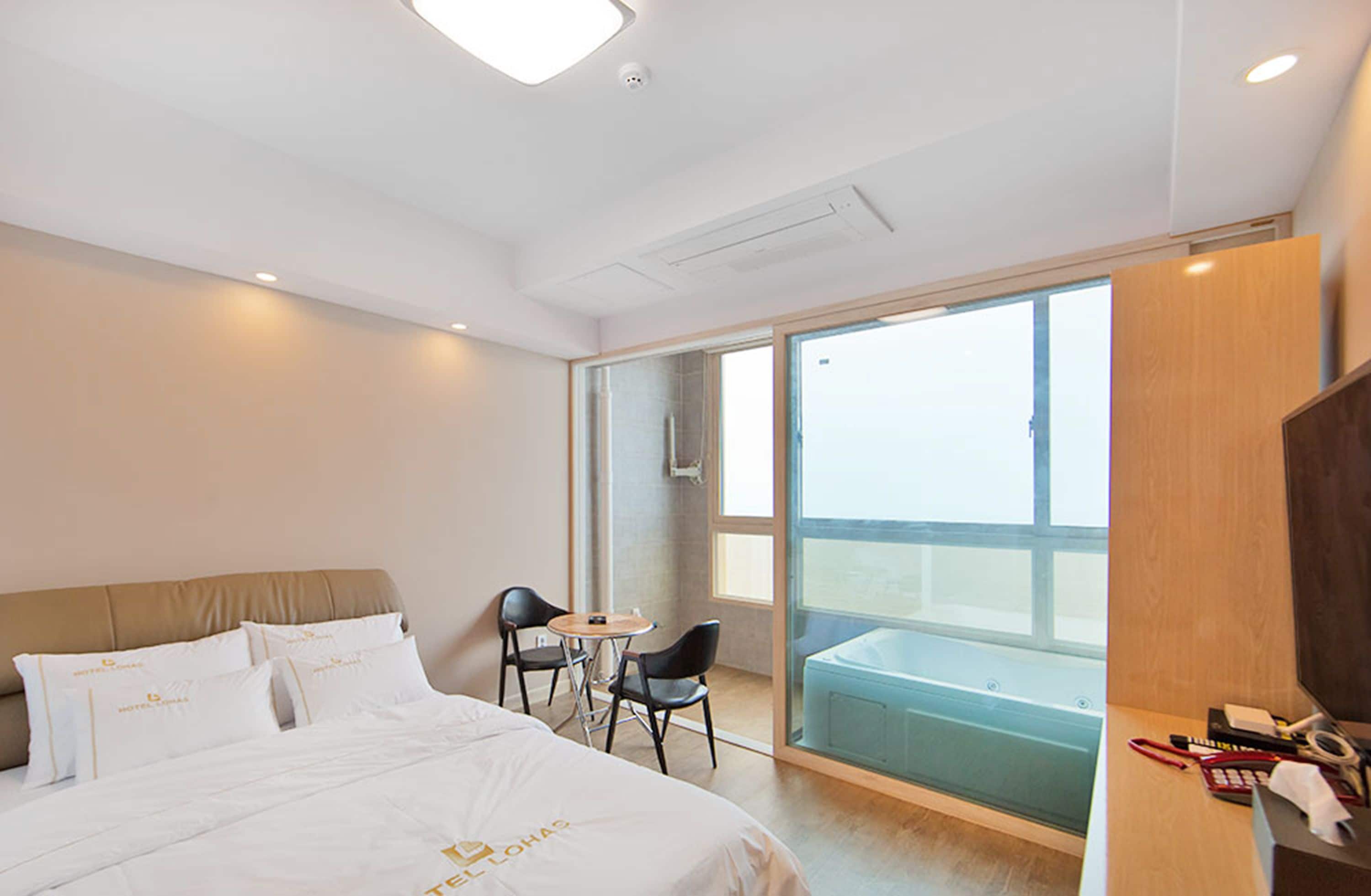 Habitación de hotel con cama, escritorio, silla y balcón con vistas.