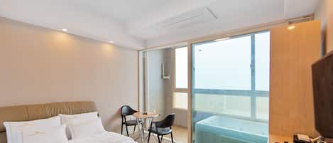 A hotel room with a bed, a desk, a chair, and a balcony with a view.