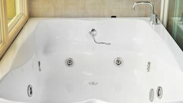 Una bañera grande, rectangular y blanca con múltiples grifos y un desagüe.