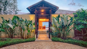 A modern house with a wooden entrance, a patio with a table and chairs, and a view of the ocean. - Borneo Eagle Resort (Kota Kinabalu)