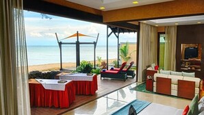 A hotel room with a large bed, a seating area with a view of the beach, and a dining table with a view of the ocean. - Borneo Eagle Resort (Kota Kinabalu)
