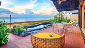 A covered outdoor seating area with a view of the sea, featuring a round table and wicker chairs. - Borneo Eagle Resort (Kota Kinabalu)