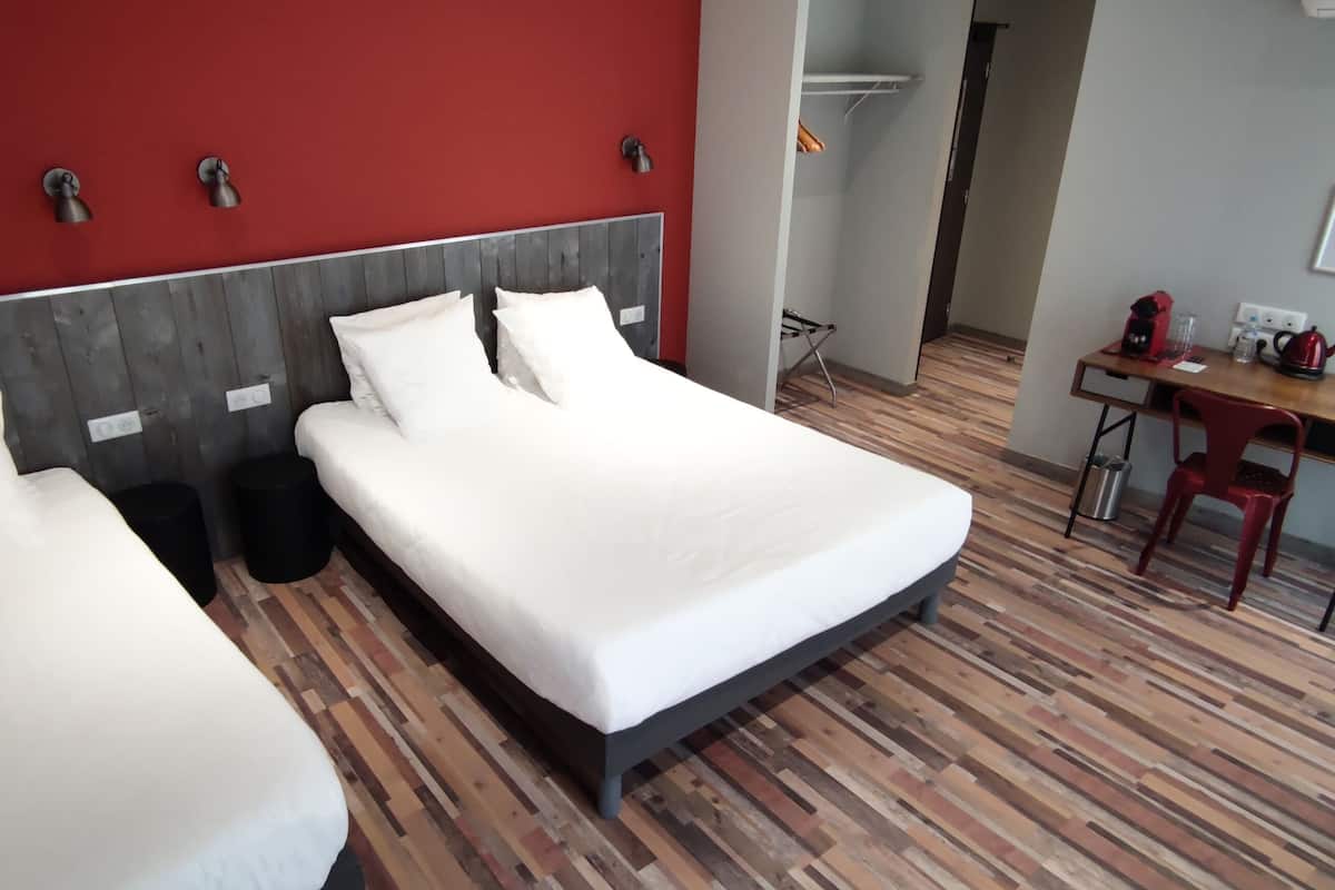 A hotel room with two beds, a desk, and a chair.