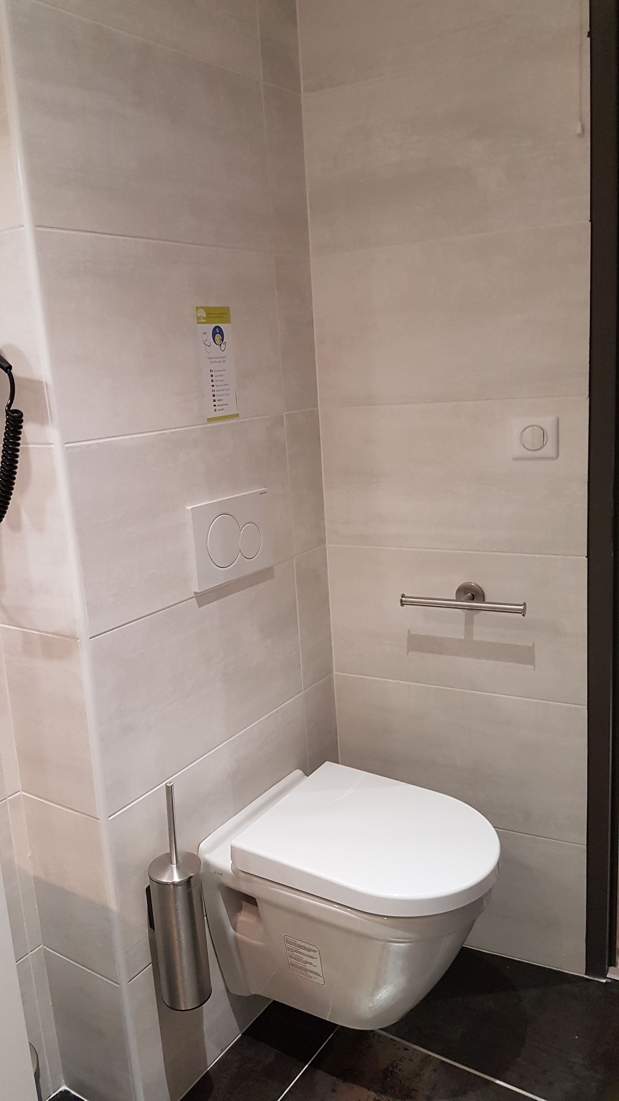 Et lille, moderne badeværelse med toilet, håndehåndtørrer og håndklædestang.