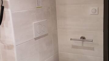 Ein kleines, modernes Badezimmer mit Toilette, Handtrockner und Handtuchhalter.