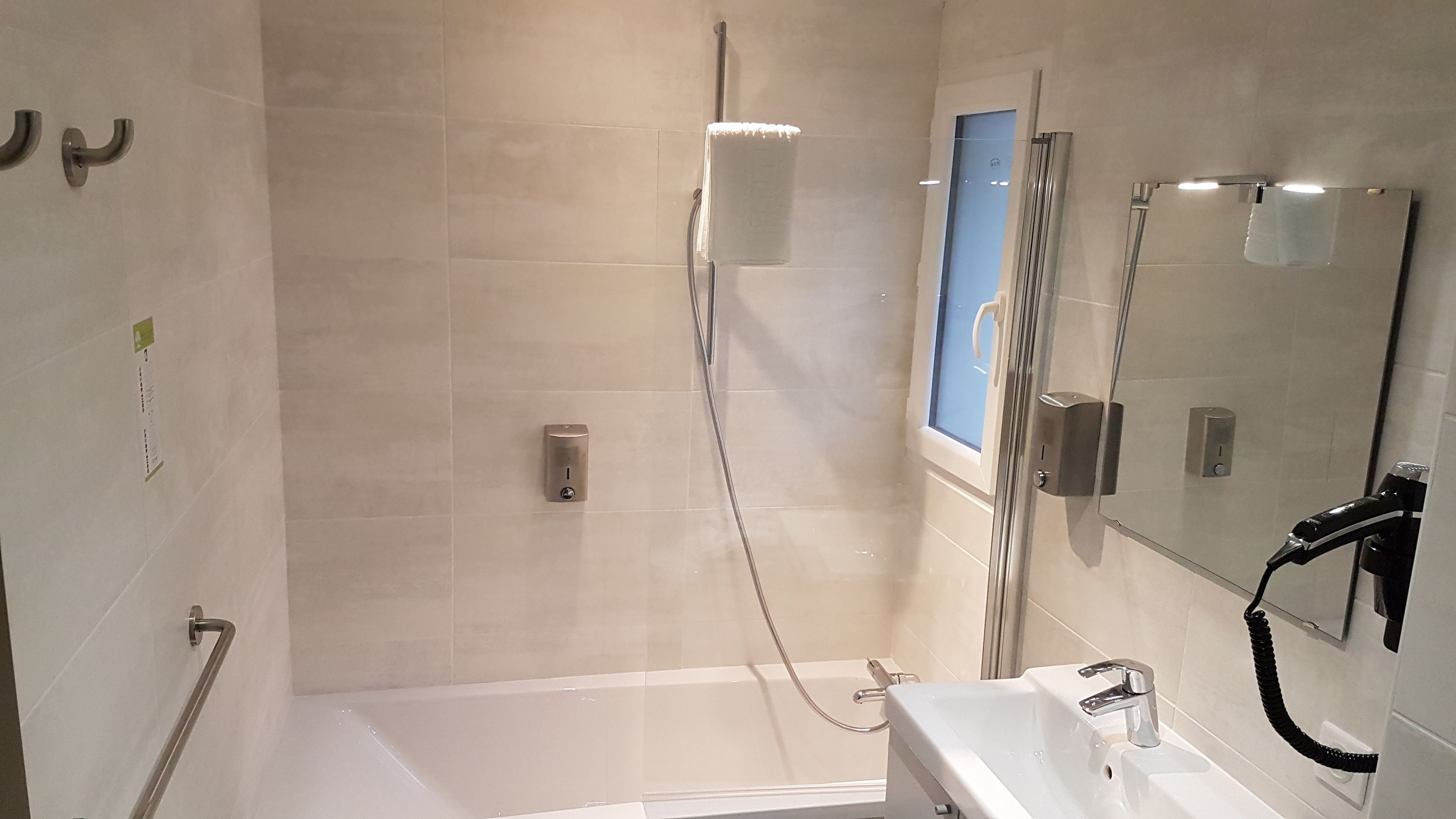 Un baño moderno con cabina de ducha de vidrio, bañera y lavamanos con espejo.