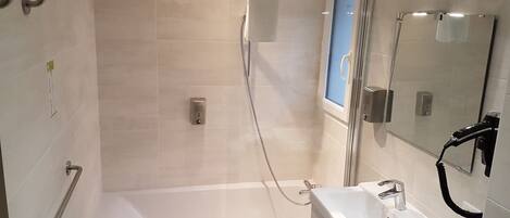 Un baño moderno con cabina de ducha de vidrio, bañera y lavamanos con espejo.
