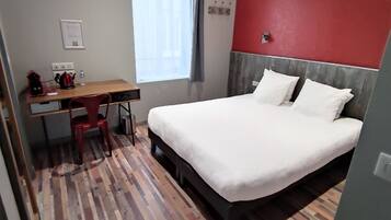 Una habitación de hotel con una cama, un escritorio y una silla.