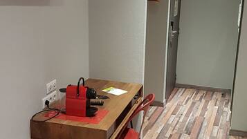 Una habitación moderna con una mesa de madera, sillas rojas, un televisor montado en la pared y un piso con diseño.