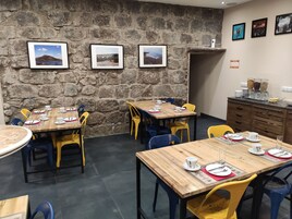 Un restaurante con paredes de piedra, mesas de madera y sillas de colores.