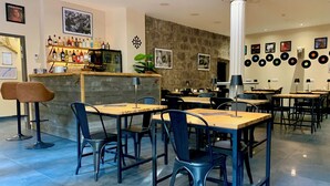 A restaurant with a bar area, multiple tables and chairs, and a wall decorated with vinyl records. - Logis Hotel Yseria - Historical Center (Agde)