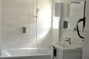 A modern bathroom with a bathtub, a shower, and a sink with a mirror.