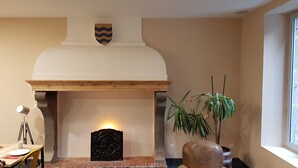 A fireplace with a stone surround, a wooden mantel, and a shield decoration above it. - Logis Hotel Yseria - Historical Center (Agde)