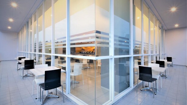 A modern conference room with glass walls, white tables, and black chairs. - Hotel 88 Bekasi By WH (Bekasi)