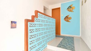 Una escalera con una partición perforada azul, piso de azulejos azules y dos piezas de arte mural con peces.