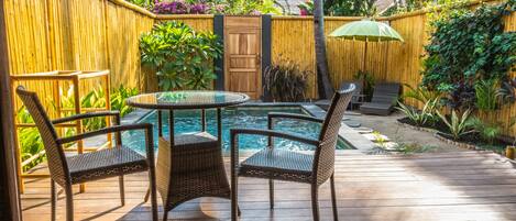 A wooden deck with a pool table, chairs, and a wooden fence.