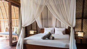 Un dormitorio espacioso con una cama grande, ropa de cama blanca y un dosel. Hay dos mesitas de noche con lámparas.