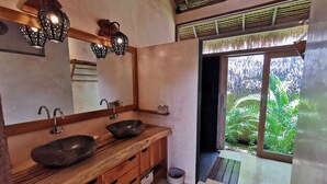 Baño con tocador de madera, dos lavamanos, un espejo y vistas al exterior.