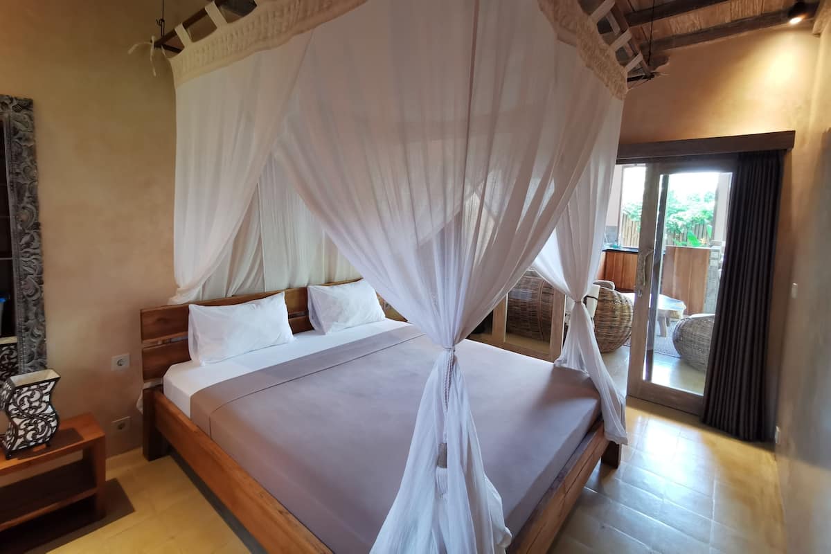 Un dormitorio con cama, cabecera de madera, ropa de cama blanca y dosel.