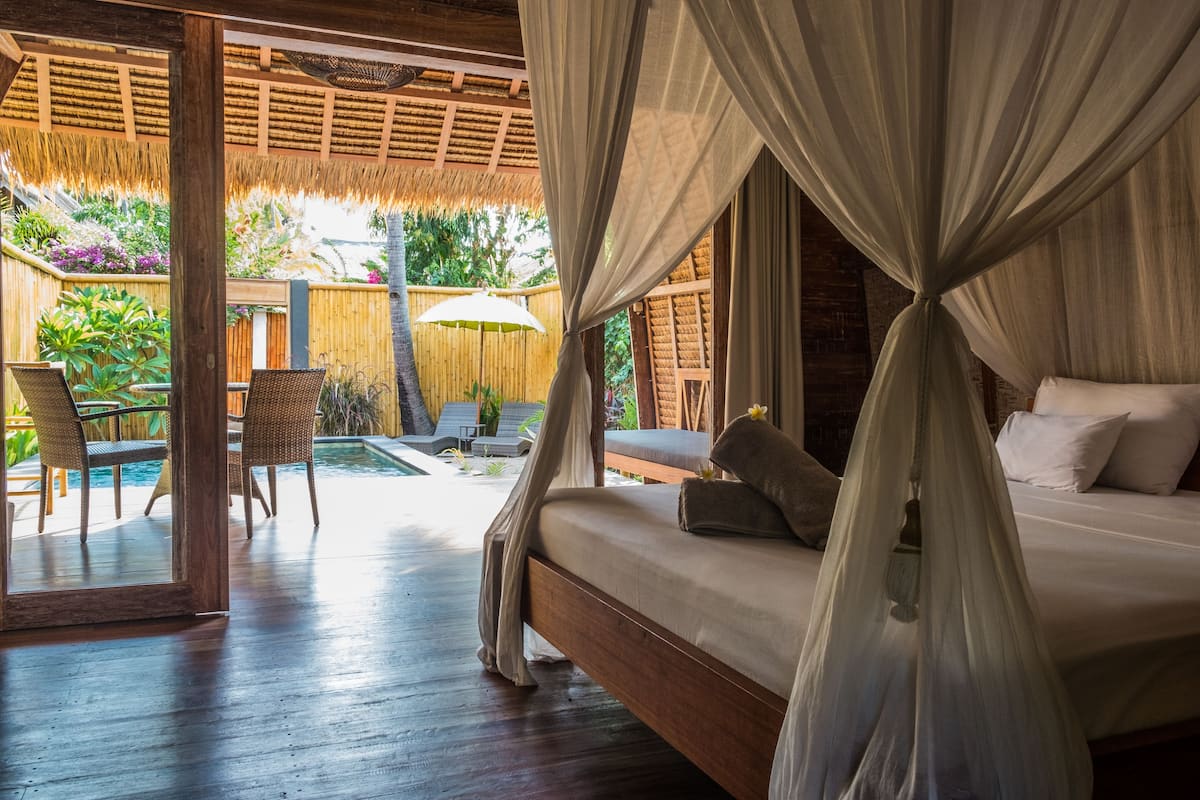 Un dormitorio con cama con dosel, una piscina pequeña y vistas al jardín.