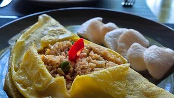 A plate with an omelette, rice, and dumplings.