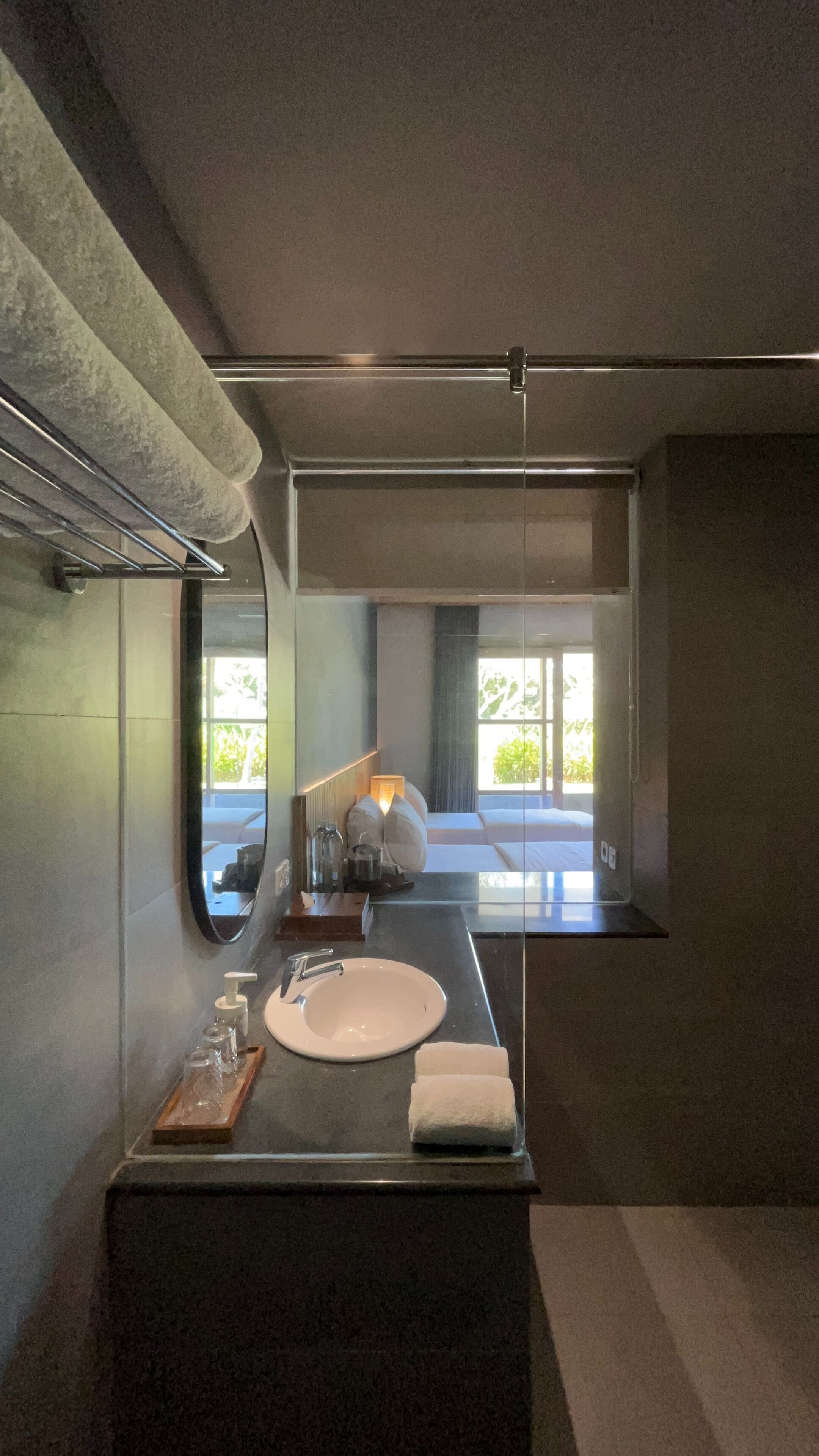 Une salle de bain moderne avec un grand miroir, un lavabo rond et un porte-serviettes.