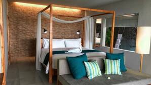 Un dormitorio moderno con cama con dosel, un sofá y un amplio ventanal con vistas a un jardín.