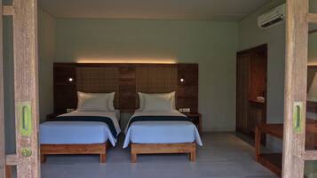 Una habitación con dos camas de madera, cada una con cabecero, ropa de cama blanca y una mesita de noche pequeña.