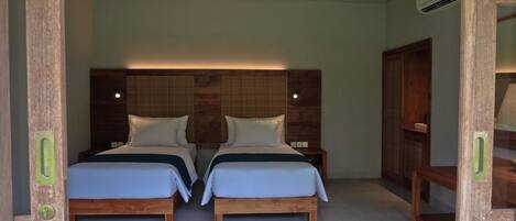 A room with two wooden beds, each with a headboard, white bedding, and a small bedside table.