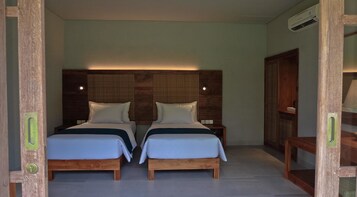 Una habitación con dos camas de madera, cada una con cabecero, ropa de cama blanca y una mesita de noche pequeña.