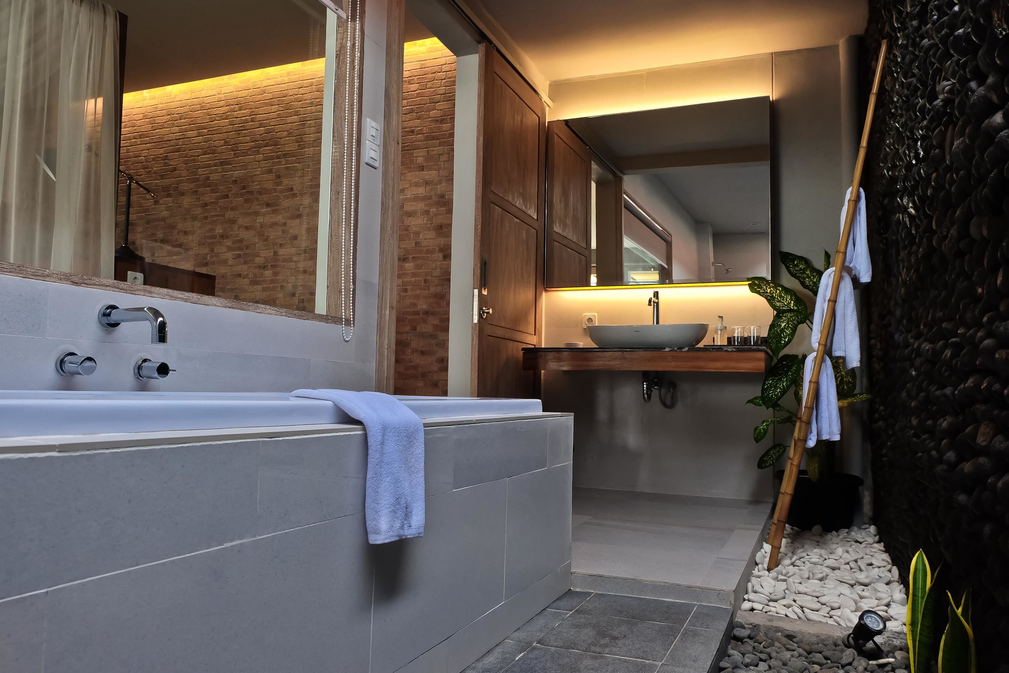 Une salle de bain moderne avec une grande baignoire, un lavabo et un miroir.