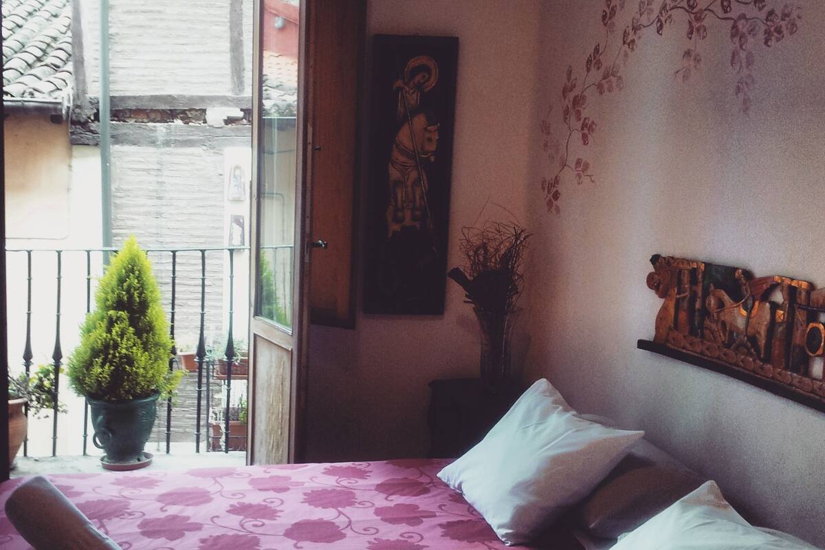Une chambre avec un lit, une plante en pot et un balcon offrant une vue.